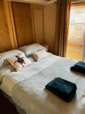 Restful retreat with a large bed, featuring a floral-patterned pillow and a plain pillow, and a convenient place to store a dark blue towel.