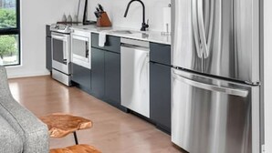 A modern kitchen with dark cabinets, stainless steel appliances, and a window providing natural light.