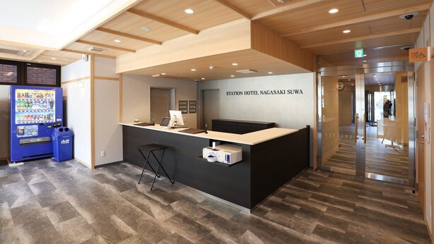En receptionsdisk med skilt, der viser 'Station Hotel Nagasaki Suwa'.