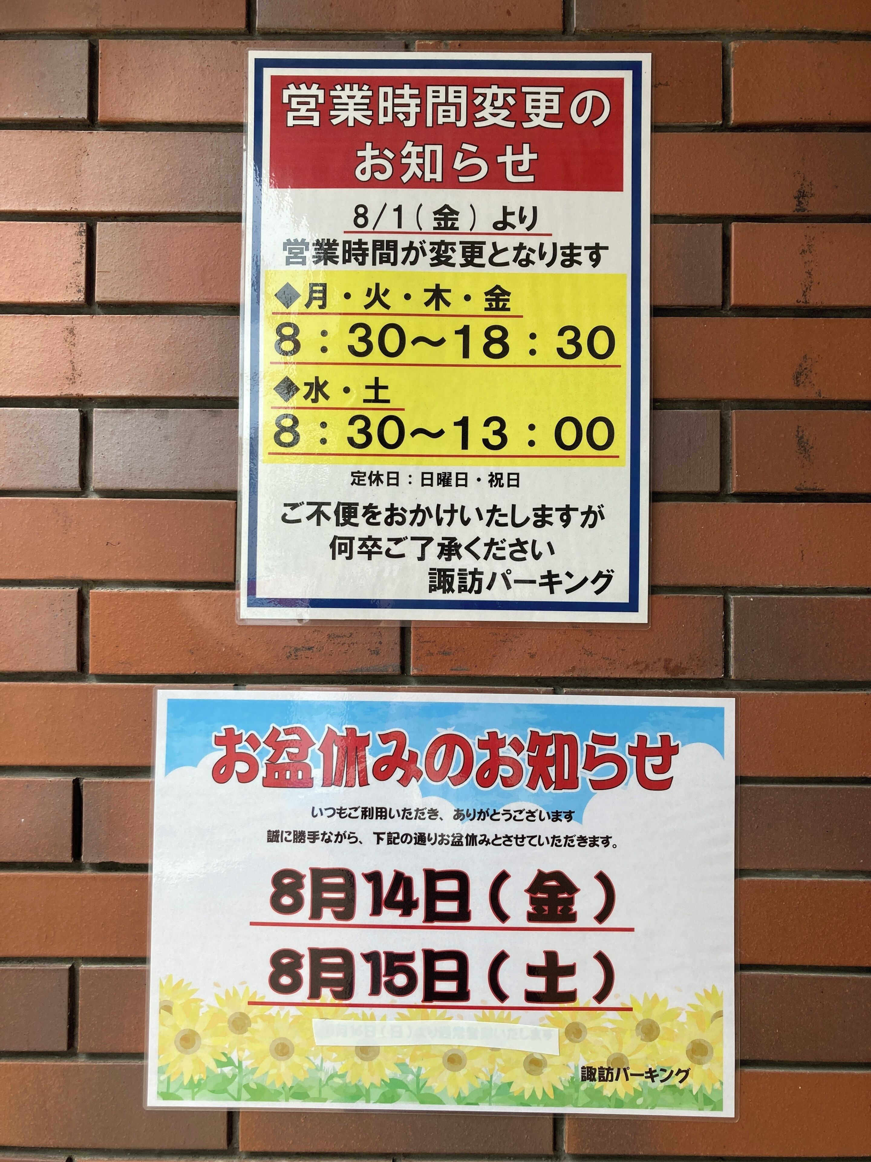 Two signs on a brick wall. The top sign indicates business hours for different days, with specific times for weekdays and weekends. The bottom sign announces a special event on August 14th and 15th.