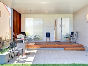 Enjoy al fresco dining and relaxation in this outdoor living space, featuring a grill station, seating area, and balcony access.