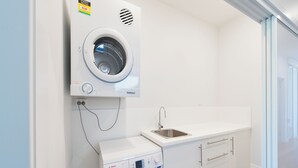 Un lavadero pequeño con lavadora Bosch, lavamanos integrado y secadora de pared.