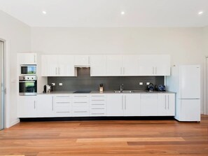 Enjoy cooking in this well-equipped kitchen with appliances, a black countertop, and a stainless steel sink.