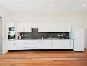Enjoy cooking in this well-equipped kitchen with appliances, a black countertop, and a stainless steel sink.
