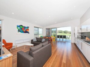 Relax in this open-plan living space with a kitchen area, featuring a sofa, dining table, and vibrant artwork.