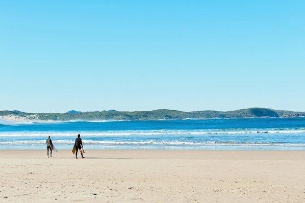 Guests can walk along the expansive beach, taking in the views of the surrounding hills and calm sea.
