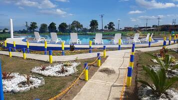 A pool area with lounge chairs and a pathway.