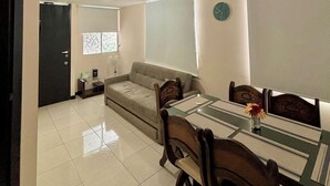 A modern living room with a sofa, dining table, chairs, and a clock on the wall. - 5 km from the Coffee Park! - Montenegro LOFT with swimming pool in Quindio - (Montenegro)