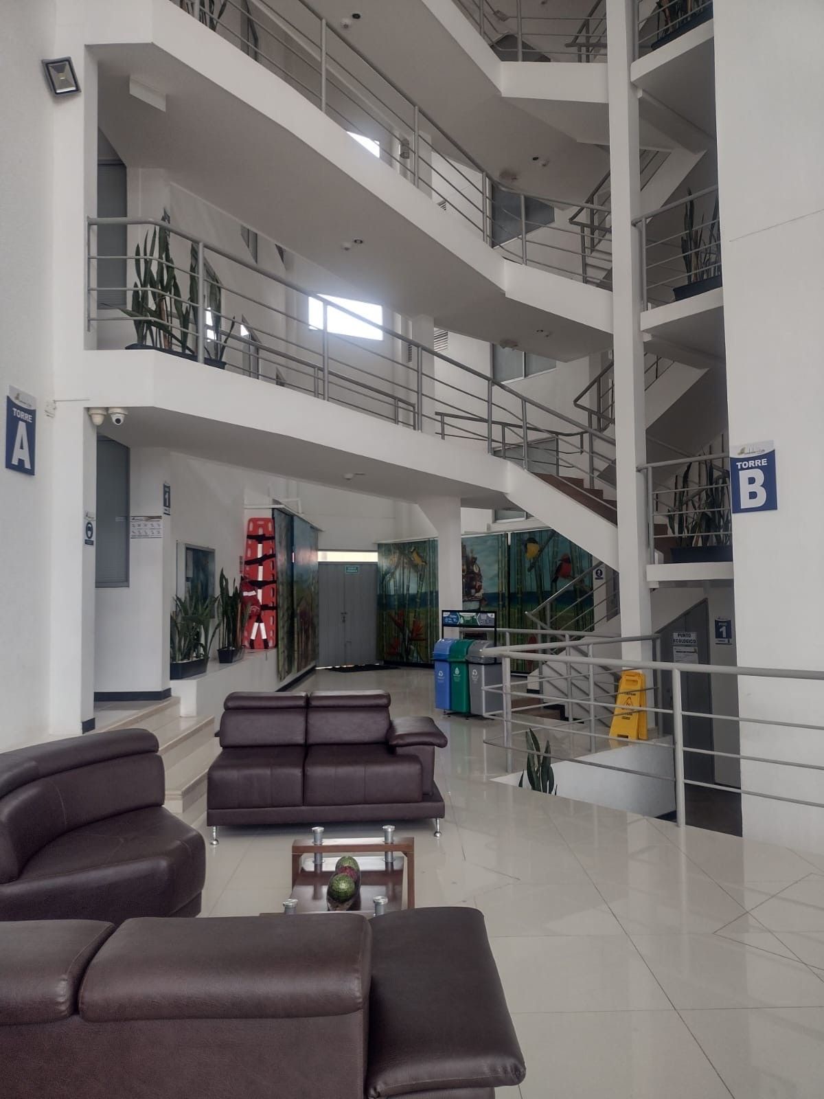 A spacious lobby with a high ceiling, multiple staircases, and seating areas.