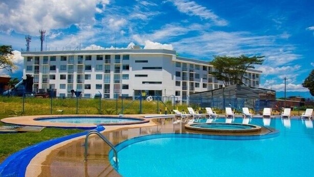 A hotel with a swimming pool, lounge chairs, and a large building with multiple floors. - 5 km from the Coffee Park! - Montenegro LOFT with swimming pool in Quindio - (Montenegro)