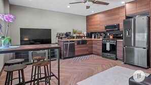 A modern kitchen with a central island, stainless steel appliances, and a ceiling fan. - Modern Luxurious Stay- Bidet- Lighted Mirror (Rapid City)