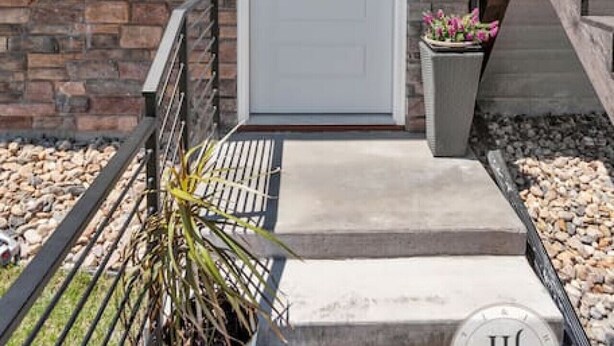 A modern house with a white front door, a stone foundation, a small porch, and a potted plant. - Modern Luxurious Stay- Bidet- Lighted Mirror (Rapid City)