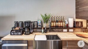A modern bar area with coffee machines, a variety of beverages, and a small plant. - Modern Luxurious Stay- Bidet- Lighted Mirror (Rapid City)