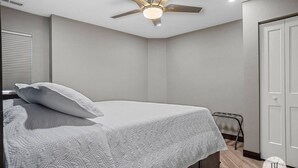 A bedroom with a bed, a ceiling fan, and a door. - Modern Luxurious Stay- Bidet- Lighted Mirror (Rapid City)