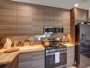 Eine moderne Küche mit Holzschränken, einem Edelstahlherd, einer Mikrowelle und einem Kühlschrank.