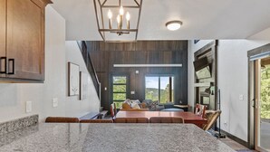 Una cocina moderna con encimeras de granito, una zona de comedor con mobiliario de madera y un amplio ventanal con vistas al exterior.