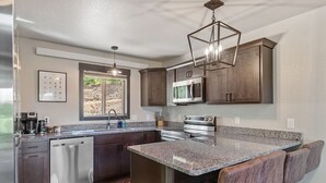 Una cocina moderna con encimeras de granito, electrodomésticos de acero inoxidable y armarios de madera oscura.