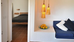 Una habitación con una cama, un sofá azul, un cuenco de limones y lámparas colgantes.