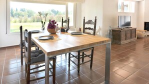 Un comedor con una mesa de madera, sillas y vistas al exterior.