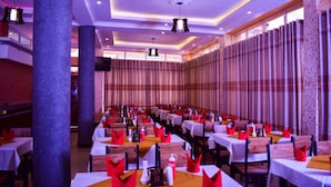 Un salón de banquetes con mesas dispuestas para un evento formal, con un techo alto con iluminación empotrada y un gran pilar.