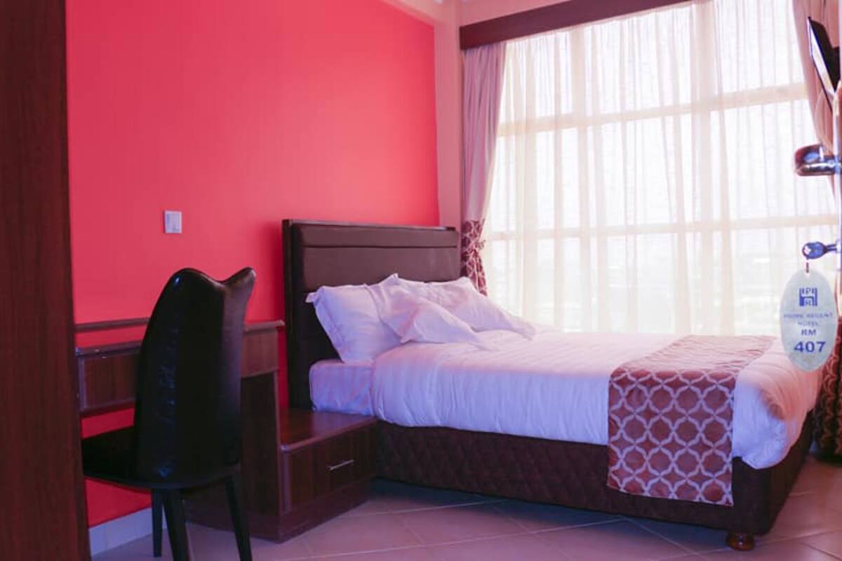A bedroom with a bed, a desk, and a chair.
