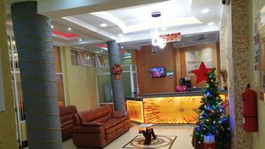 Un hall de hotel con una recepción, un árbol de Navidad, un pilar grande y un sofá de cuero.