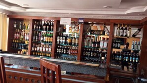 Una zona de bar con sillas de madera y un mostrador repleto de botellas de licores.
