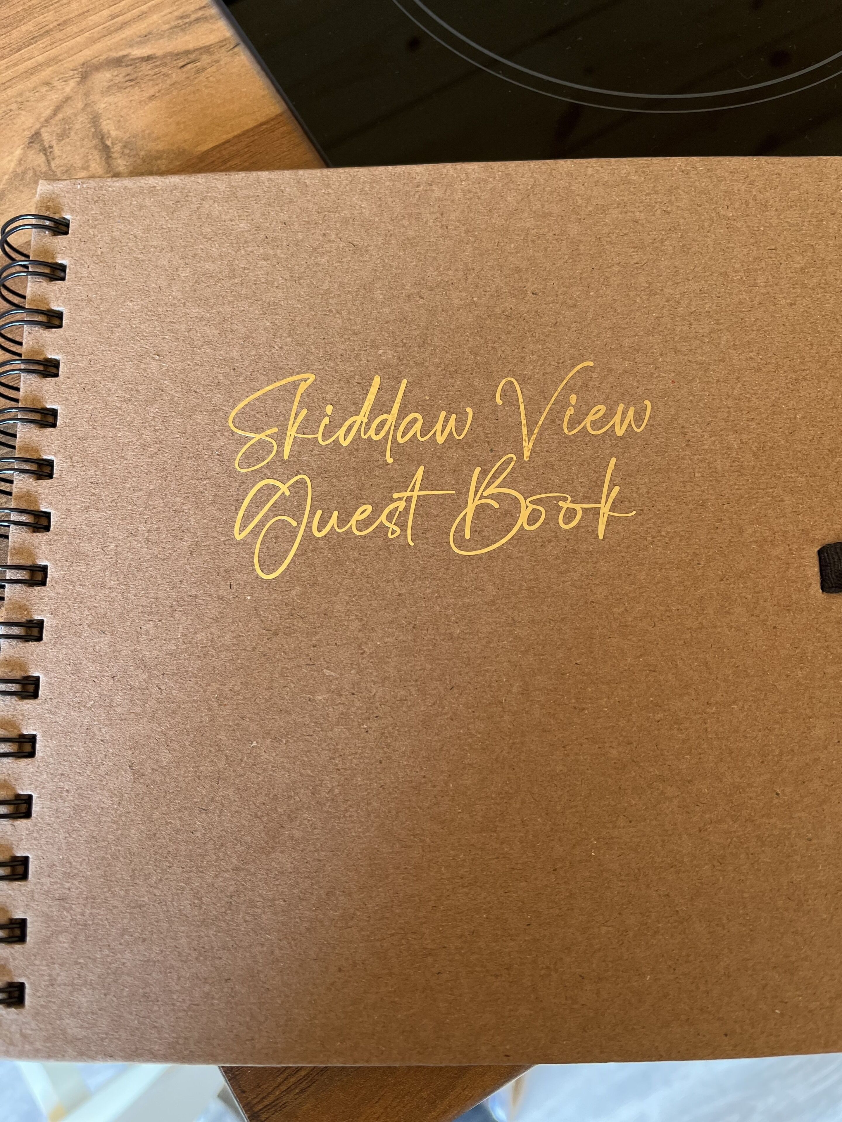 En spiralbunden anteckningsbok med texten ”Fiddaw View Guest Book” tryckt på omslaget.