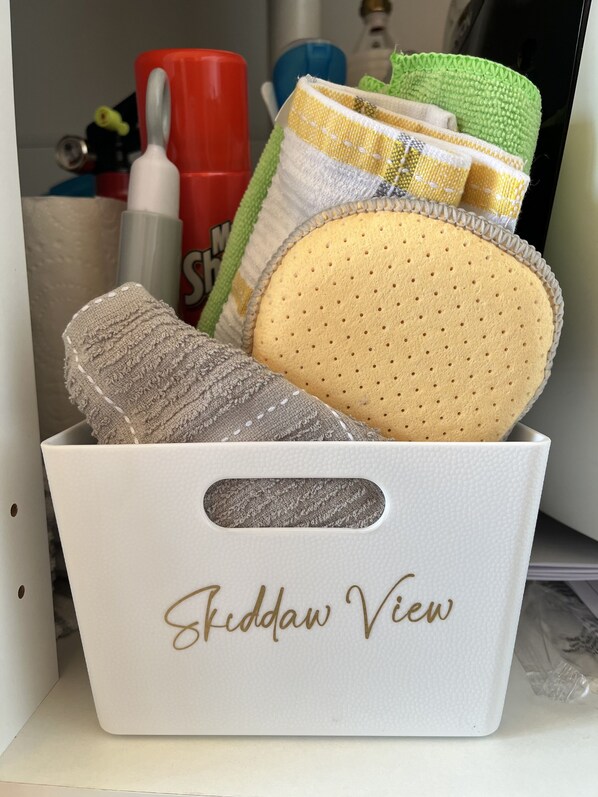 Una caja de almacenamiento con la etiqueta "Friddaw View" que contiene varios objetos, incluyendo un elemento gris con textura, una esponja amarilla y una toalla verde y blanca.