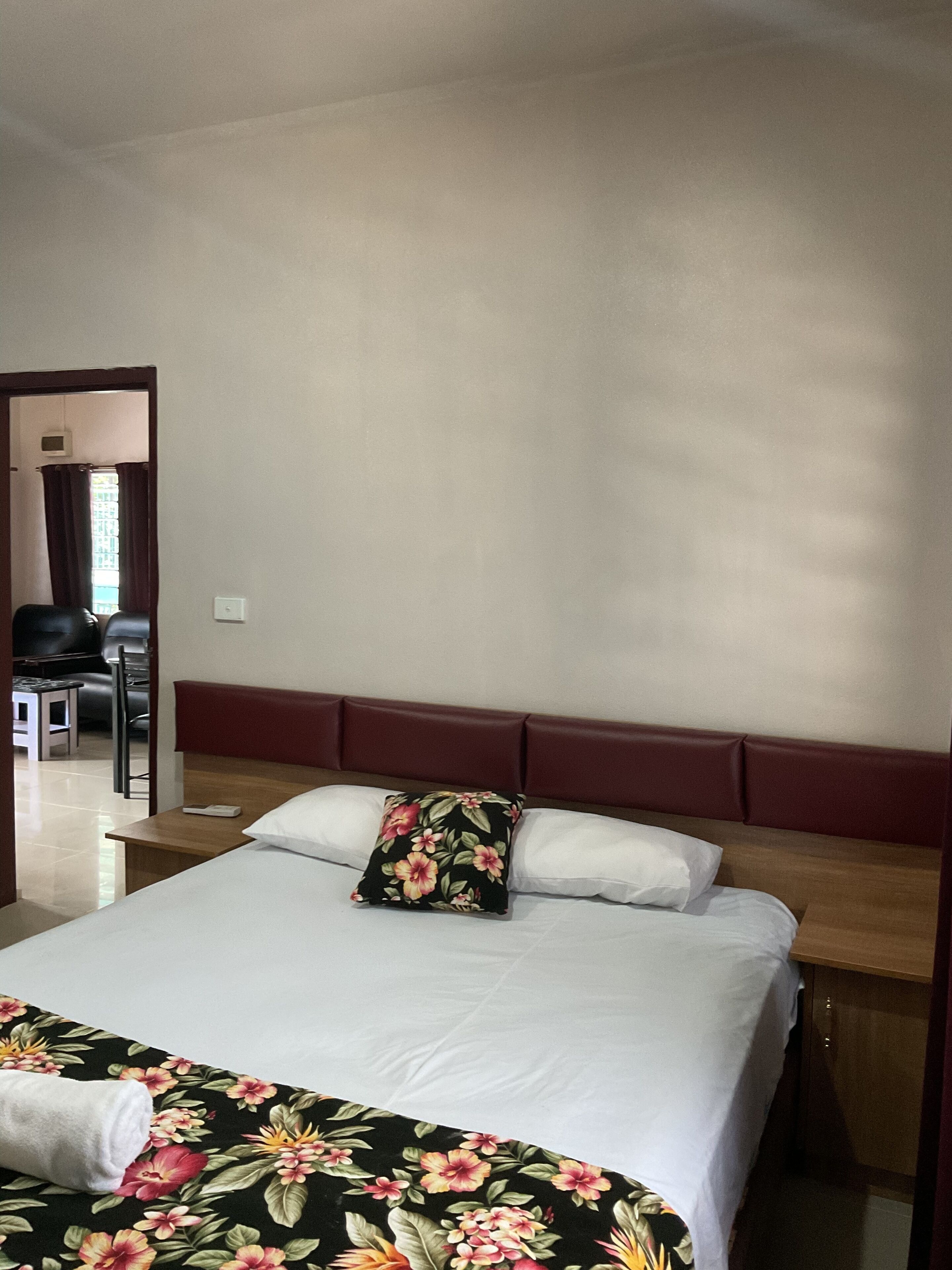Een hotelkamer met een bed, een houten hoofdeinde, een nachtkastje en een spiegel.