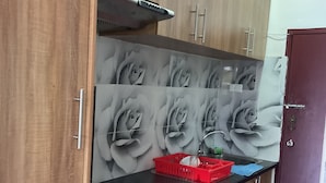 A kitchen with wooden cabinets, a gas stove, a red basket, and a patterned backsplash. - Fox Homestay (Suva)