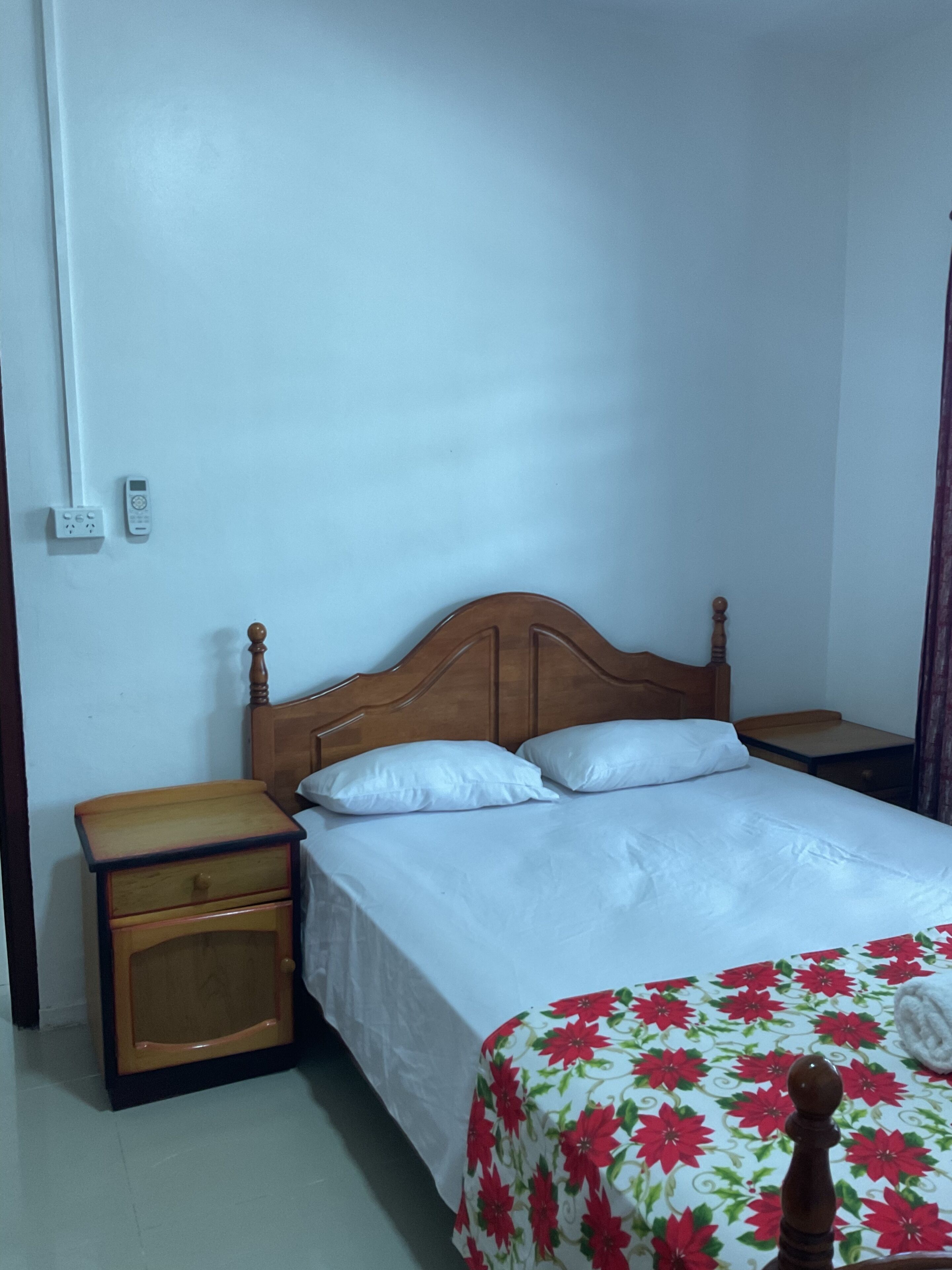 A single bed with a wooden headboard, a bedside table, and a nightstand.