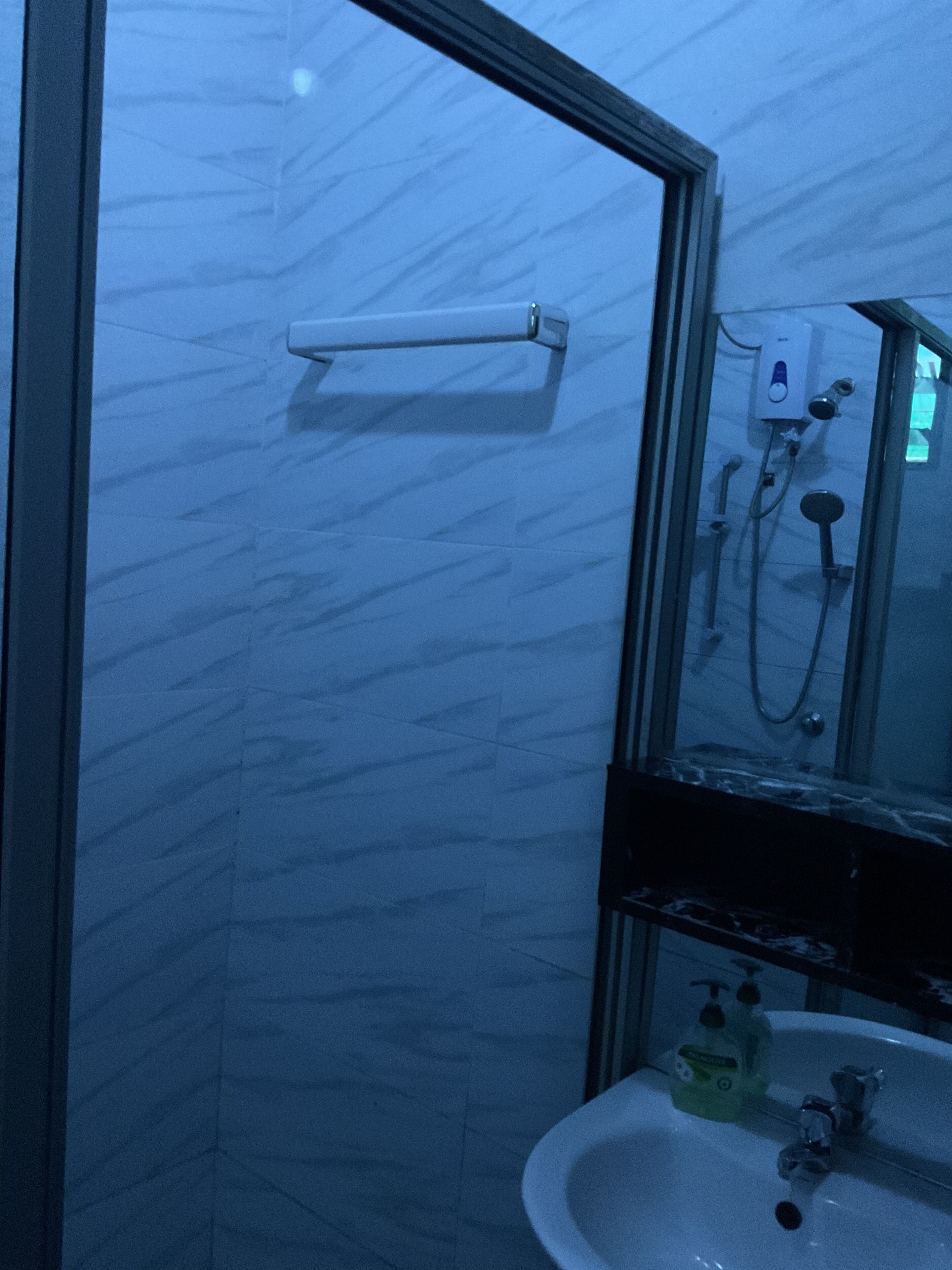 A bathroom with a glass door, a white sink, a mirror, and a shower unit.