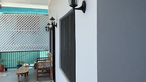 A balcony with a wooden table and chairs, potted plants, and a wall-mounted lantern. - Fox Homestay (Suva)