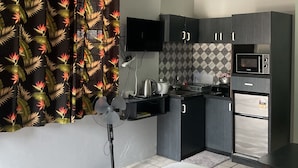 A modern hotel room with a bed, a desk, a flat-screen TV, a microwave, and a refrigerator. - Fox Homestay (Suva)