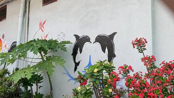 A wall with a mural of two dolphins and surrounding greenery.