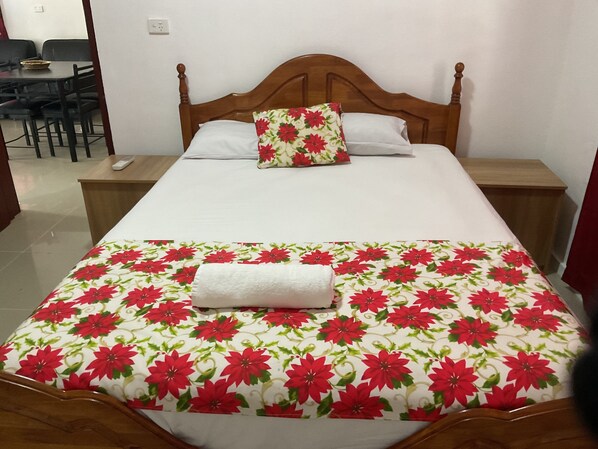 A neatly made bed with a floral bedspread, a wooden headboard, and two bedside tables with lamps.
