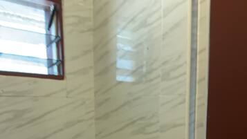 Un baño con inodoro, secamanos y un dispensador de papel higiénico en la pared.