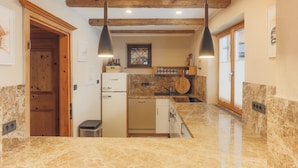 A kitchen with marble countertops, wooden beams, a refrigerator, and pendant lighting. - Appartement  Streifblick
Wohlfühlappartement für bis zu 6 Personen   (Kitzbühel)