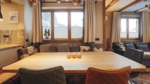 A cozy dining area with a large wooden table, cushioned seating, and pendant lighting. - Appartement  Streifblick
Wohlfühlappartement für bis zu 6 Personen   (Kitzbühel)