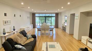 A modern living room with a black sofa, a coffee table, and a dining area with a white table and chairs.