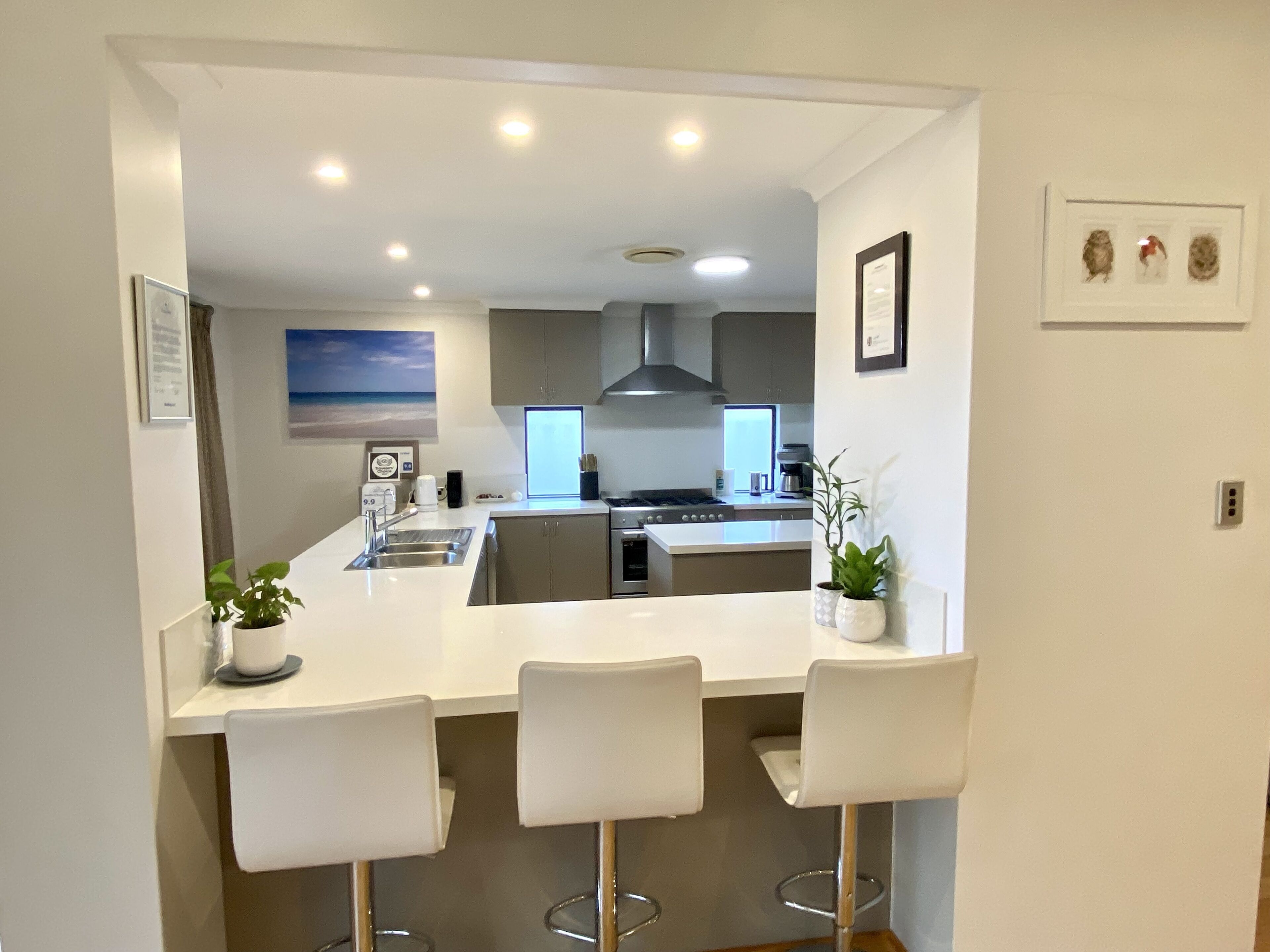 A modern kitchen with a central island, bar stools, and a view of the living area.