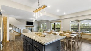 Una cocina espaciosa con una isla grande, suelo de madera y un área de comedor con varias sillas.