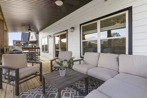 Un patio esterno con divano, sedie, tavolo e zona barbecue.