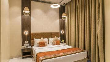 Habitación de hotel con una cama grande, dos mesitas de noche, un tablero auxiliar, un panel de control en la pared y una ventana con cortinas.