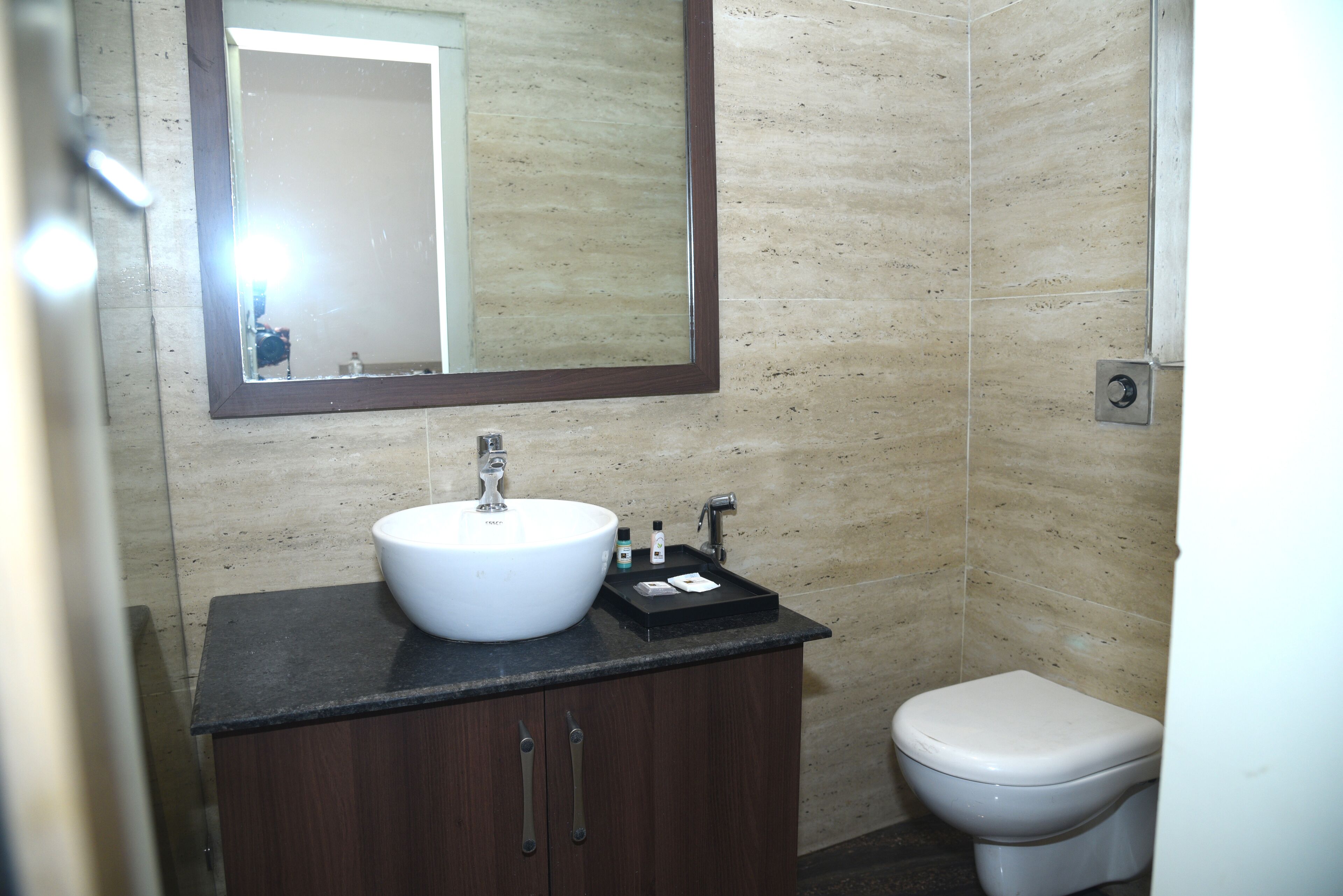 A bathroom with a white sink, dark wooden cabinet, and a white toilet.