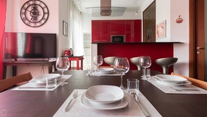 Un coin repas avec une table dressée pour quatre personnes, comprenant des assiettes, des verres et des couverts.