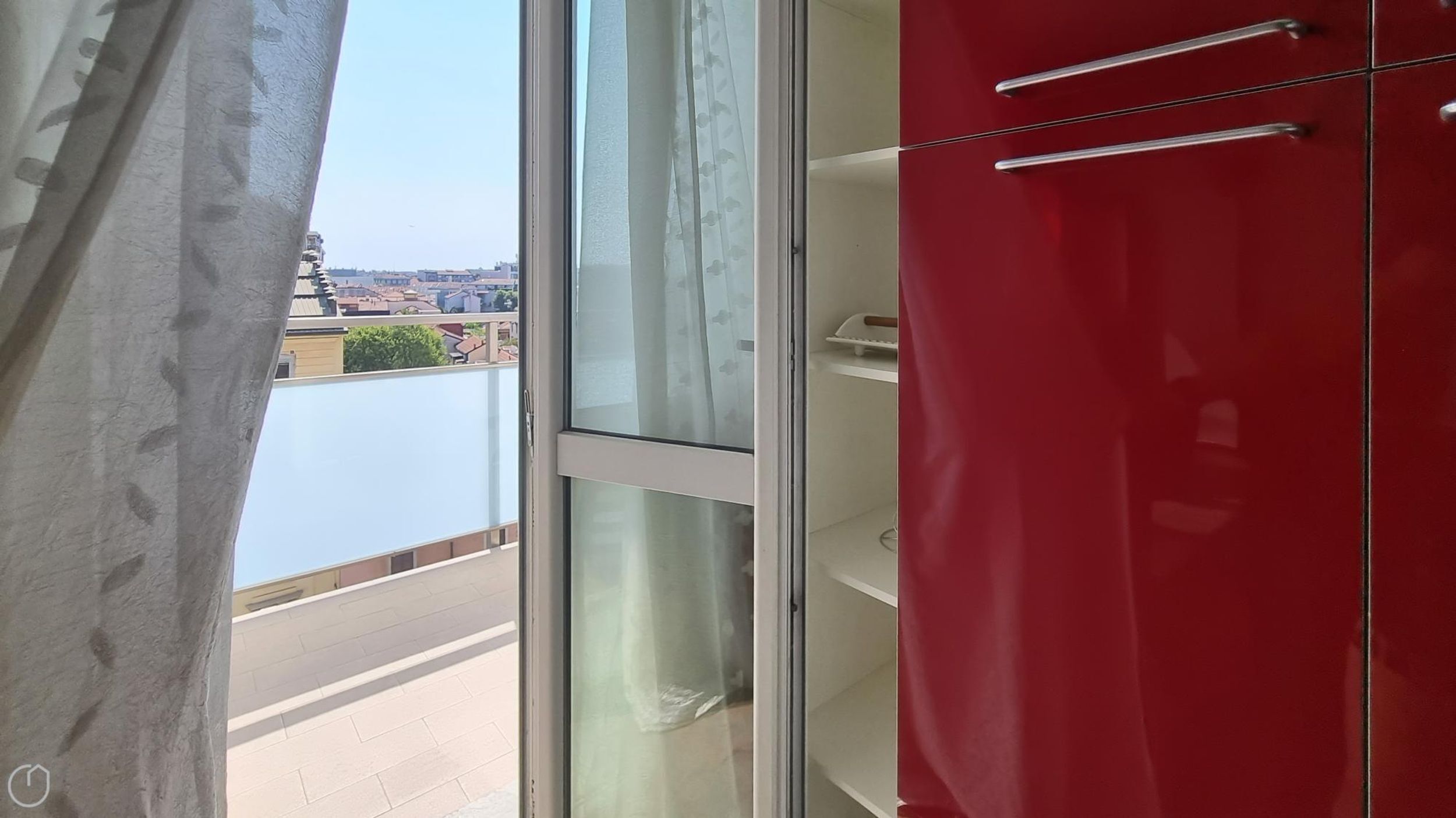 Une pièce avec une armoire rouge, une porte-fenêtre coulissante et une vue sur le paysage urbain.