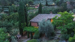 Une maison de campagne, entourée d’une végétation luxuriante, avec un chemin de pierres menant à l’entrée.