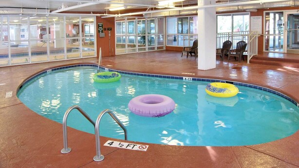Una piscina interior con agua cristalina, un indicador de profundidad y tres flotadores inflables.